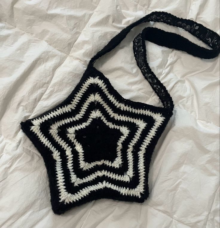 a black and white crocheted bag sitting on top of a white bed sheet