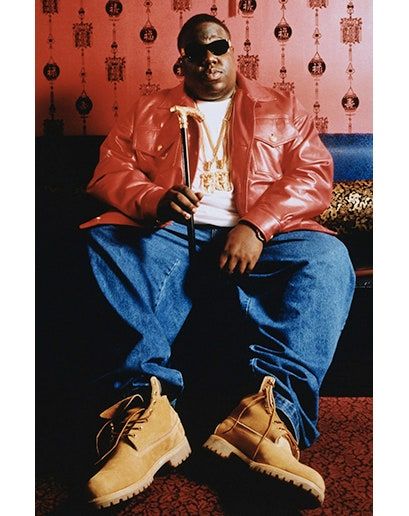 a man sitting on top of a blue couch wearing a red leather jacket and yellow shoes