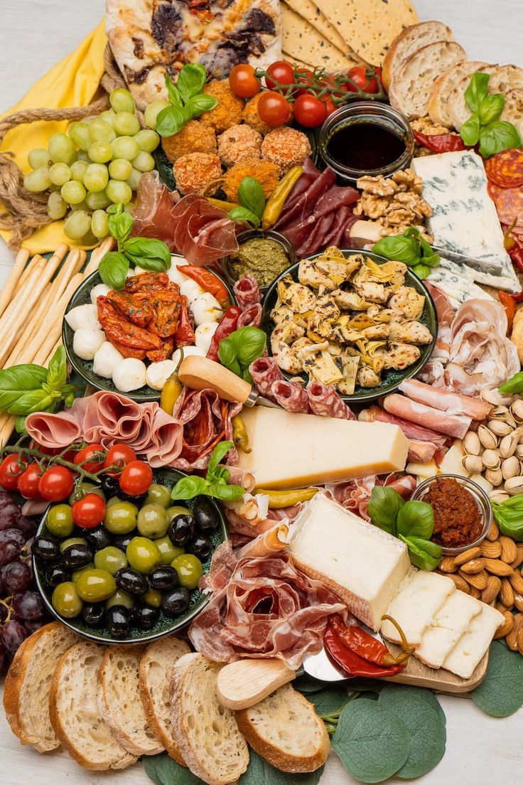 an assortment of cheeses, meats, and vegetables arranged on a platter