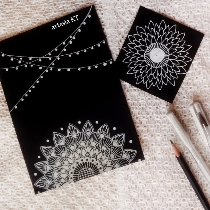 two black notebooks with white designs on them