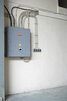 an electrical box mounted to the side of a white wall with wires and plugs