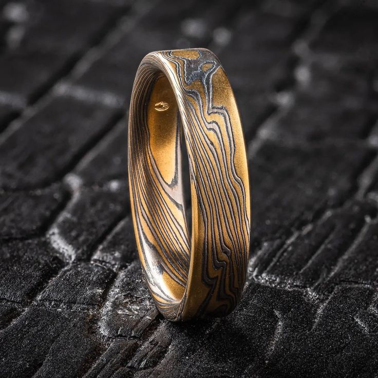 "* Price may vary depending on ring size, please inquire with us directly with your needed size for accurate pricing! This custom Mokume Gane wedding ring features a customized version of our Flare Palette with an etched and oxidized finish. This Flare palette consists of 18kt Yellow Gold, Palladium, and Sterling Silver.  This custom palette has thicker yellow gold layers and thinner palladium and silver for a more prominently gold appearance. Pattern: Twist  Palette: Custom Flare Finish: Etched & Oxidized Width Shown: 5mm Size Shown: 10.5 Profile: Flat Price does NOT include stones or setting fees. We care about customer service and would like to hear from you! Please contact us to help create your treasured item, we take your concerns and requests to heart and will work together to creat Adjustable Copper Wedding Rings, Adjustable Copper Rings For Wedding, Artisan Etched Jewelry For Wedding, Mokume Gane Ring Wedding, Rustic Color Palettes, Mokume Gane Ring, Boo Thang, Twist Pattern, Mokume Gane