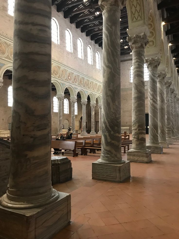 the inside of a building with columns and benches