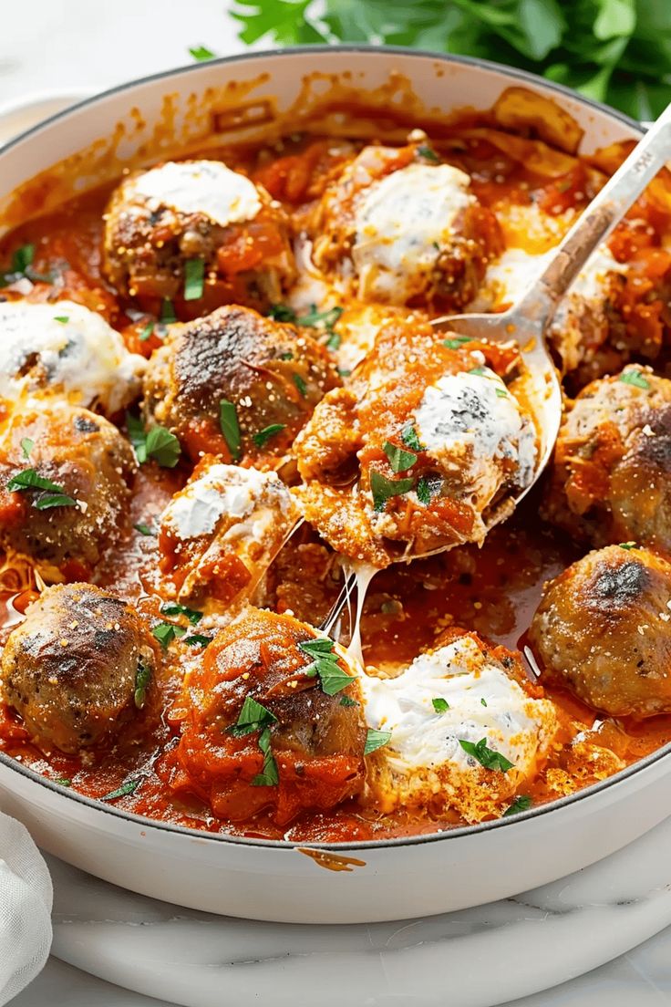 a white bowl filled with meatballs covered in marinara sauce and parmesan cheese