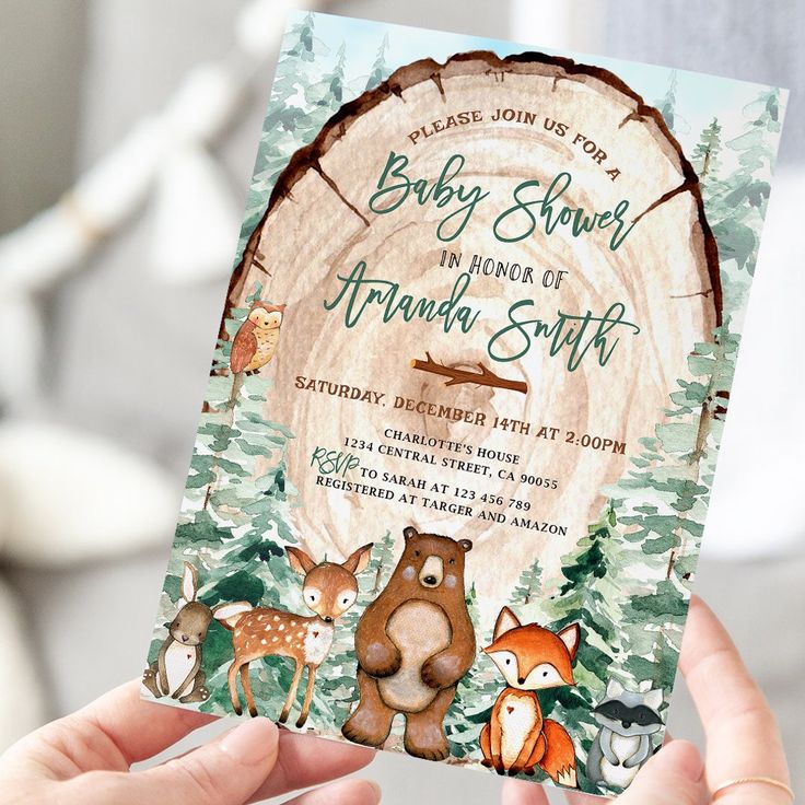 a person holding up a baby shower in front of a tree stump with animals on it