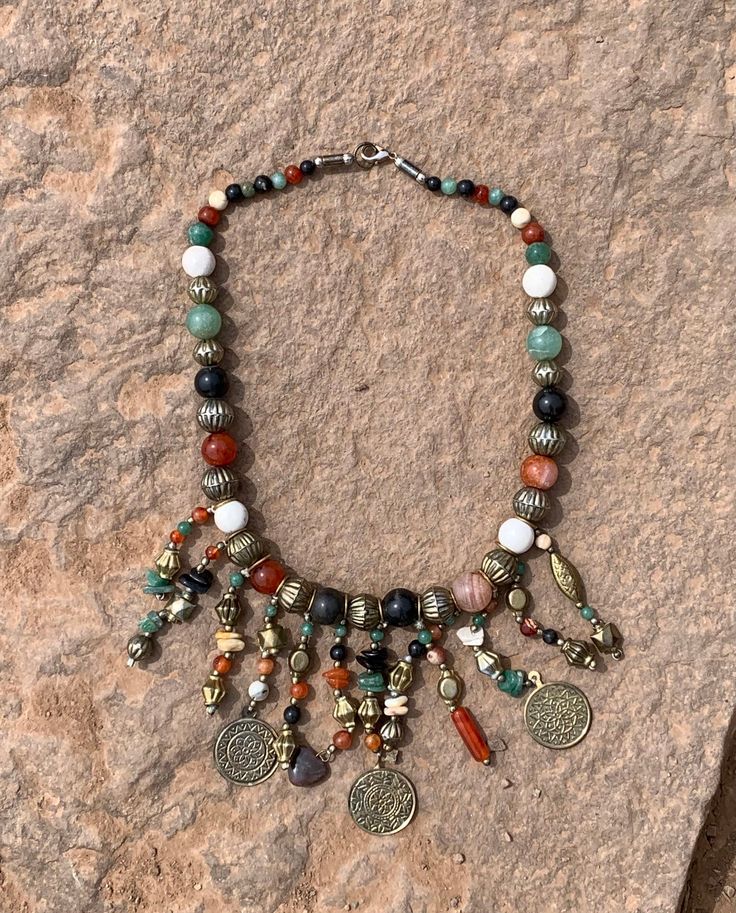 "Vintage Boho Tribal Mixed Gemstone Brass Bead Coin Fringe Necklace 21\" Up for offer is a unique vintage, possibly ethnic middle eastern, boho tribal mixed gemstone and gold tone metal bead and repousse coin fring necklace. The gemstone beads appear to consist of carnelian, jade, hematite (or some other dark stone), and the white ones appear to be made of baked and glazed clay. The metal beads appear to be a metal alloy that resembles brass. The clasp is a lobster claw clasp. Measurements Lengt Vintage Gemstone Beads Jewelry For Healing, Vintage Handmade Dangle Beaded Necklaces, Vintage Polished Bead Jewelry For Festivals, Vintage Jewelry With Polished Beads For Festivals, Bohemian Crystal Necklace With Polished Beads For Festivals, Vintage Jewelry With Round Natural Stones, Vintage Polished Beads Jewelry For Festival, Bohemian Beaded Necklace With Polished Round Beads, Bohemian Round Beaded Necklace With Polished Beads