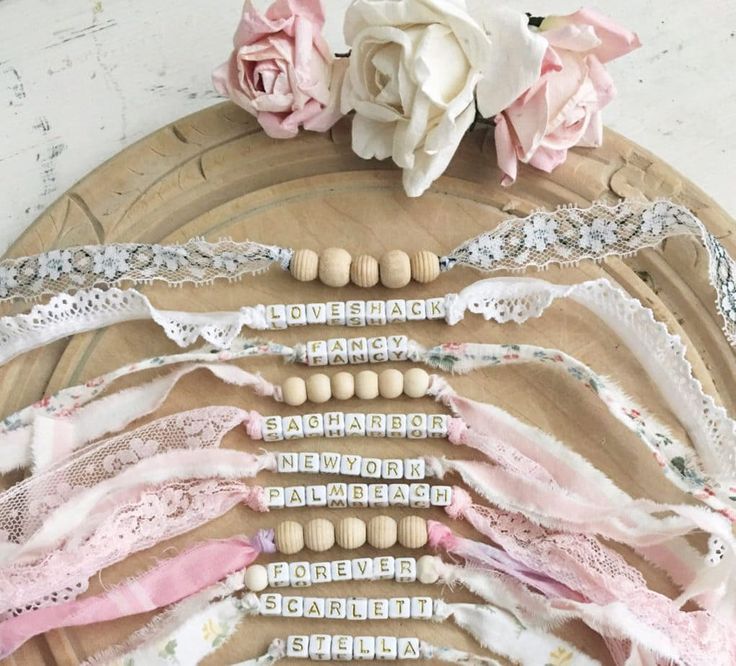 several different types of laces and beads on a wooden platter with flowers in the background