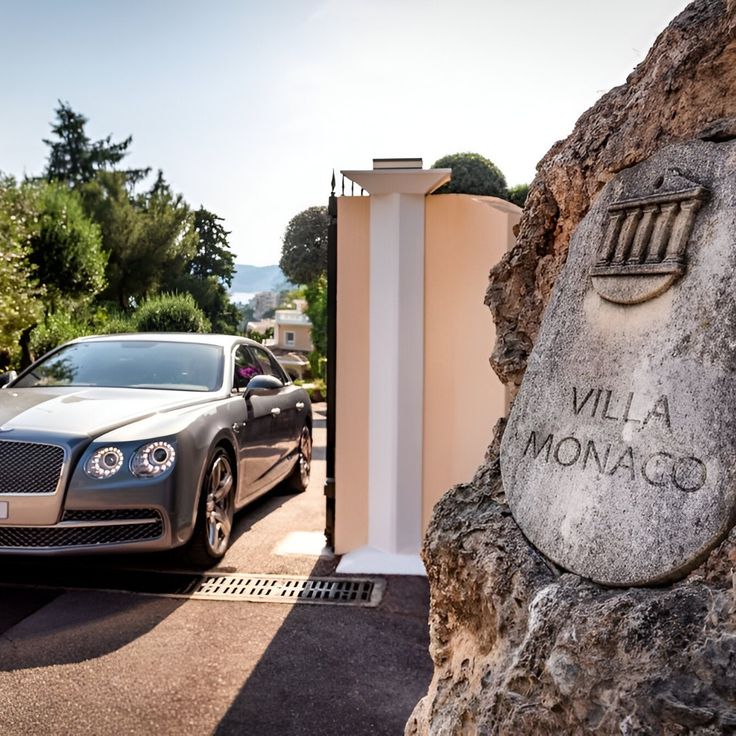 a car parked in front of a stone monument with the name villa monaco on it