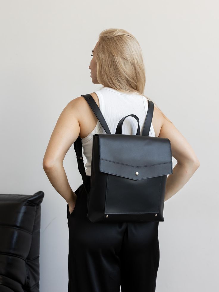 The black leather women's backpack is a chic and versatile accessory designed for the modern woman who values both style and functionality. This minimalist backpack features a sleek, streamlined design that makes it an ideal city rucksack for daily use. Its spacious interior provides ample room for essentials, while the comfortable straps make it easy to carry throughout the day. As a stylish work bag, it seamlessly transitions from casual outings to professional settings, ensuring you look poli Modern Soft Leather Satchel Backpack, Minimalist Leather Travel Backpack, Modern Leather Satchel Backpack For Everyday, Office Backpack With Leather Backing, Modern Leather Satchel Backpack For Commuting, Office Leather Backpack With Adjustable Strap, Modern Leather Backpack With Adjustable Strap, Minimalist Backpack For Everyday Use, Minimalist Leather Backpack With Adjustable Strap For On-the-go