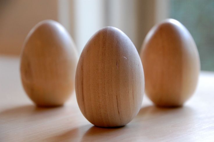 three wooden eggs sitting on top of a table