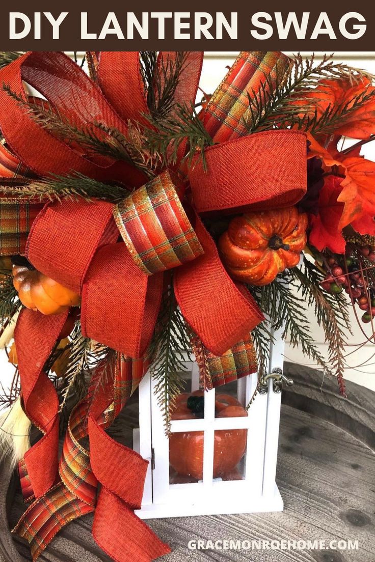 a red bow on top of a wooden box with pumpkins and greenery in it