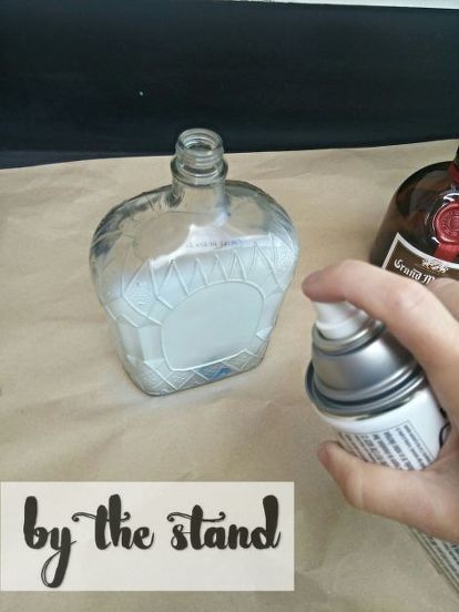 a person is holding a bottle in front of a paper with the words by the stand on it