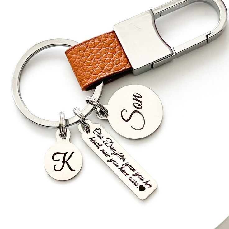 a couple of key chains that are on top of a white table with a brown leather strap