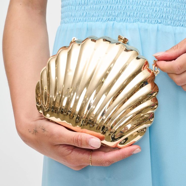 Embrace seaside charm with our Shell Elegance Evening Bag. Its captivating shell-shaped exterior, adorned with gold hardware, makes a fashion statement. The detachable chain strap and fabric-lined interior ensure practicality meets style. Item Type: Evening Clutch Material: Plastic Closure: Top Clasp Exterior Details: Shell Shaped, Gold Hardware, Detachable Chain Strap Interior Details: Fabric Lined 7.09” L x 1.57” W x 5.71” H Chic Summer Evening Bag For Events, Gold Evening Bag For Formal Summer Events, Chic Summer Formal Clutch, Chic Formal Summer Clutch, Summer Formal Clutch Shoulder Bag, Formal Summer Clutch Shoulder Bag, Gold Clutch For Formal Summer Events, Chic Summer Evening Bag For Formal Occasions, Gold Clutch For Summer Events