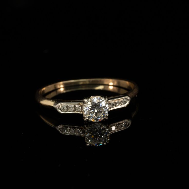 an antique diamond engagement ring on a black background