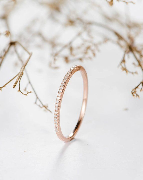 a close up of a wedding ring on a white surface with dried branches in the background