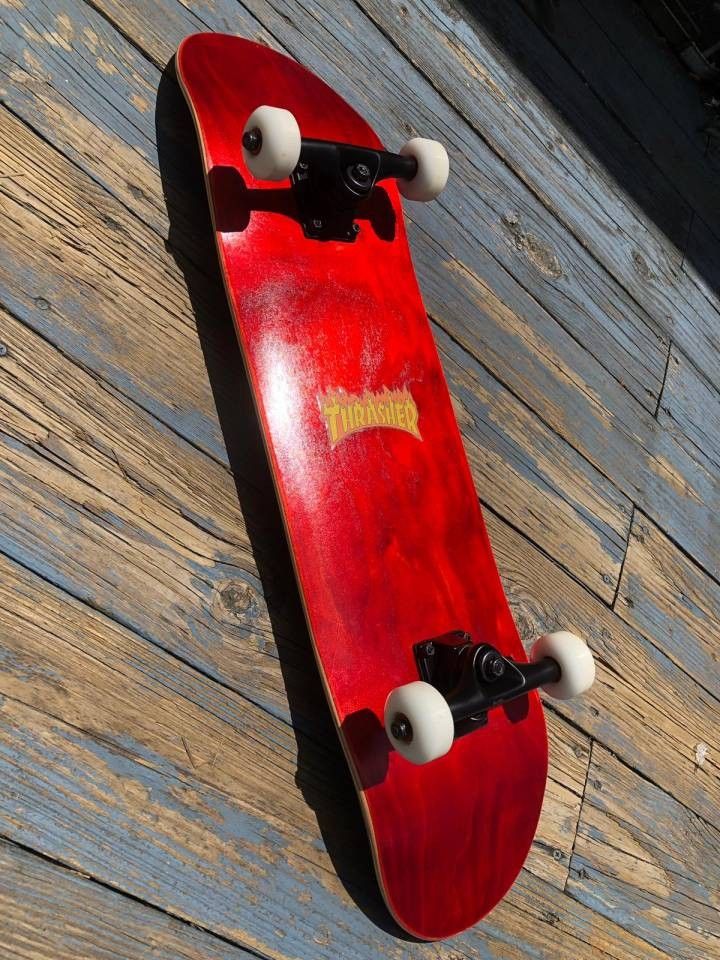 a red skateboard hanging on the side of a wooden wall