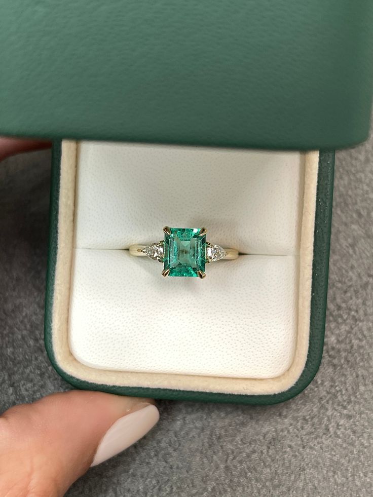 A classic Colombian emerald and diamond engagement, statement, or right-hand ring. Dexterously crafted in gleaming 14K gold this ring features a 1.81-carat natural Colombian emerald-emerald cut from the famous Chivor mines. Set in a secure prong setting, this extraordinary emerald has a bright green color and glow. This emerald has very good eye clarity with natural Jardins that occur in all earth-mined emeralds. Pear diamonds weighing 0.30pts total accent on either side of the emerald. Setting: Emerald Cut Rings Gold, Small Green Engagement Ring, Colombian Emerald Engagement Ring, Emerald Pear Engagement Ring, Crazy Rich Asians Ring, Wedding Manifestation, Square Emerald Ring, Three Stone Engagement Rings Emerald, Emerald Cut Emerald Ring