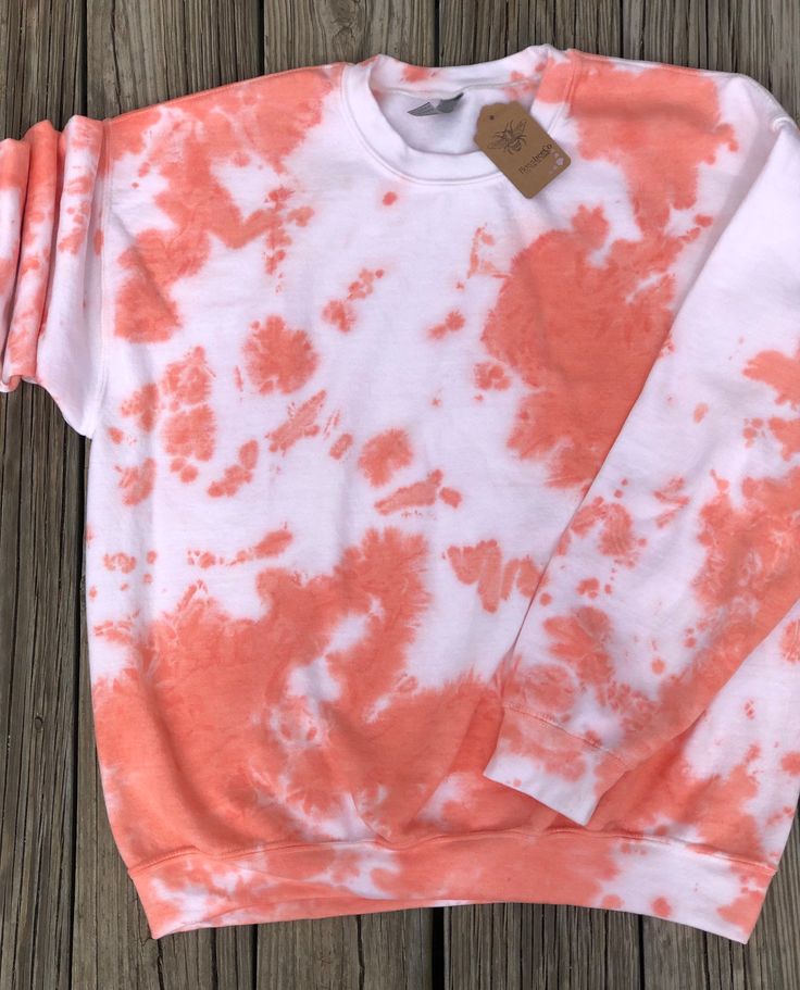 an orange and white tie dye sweatshirt on a wooden surface