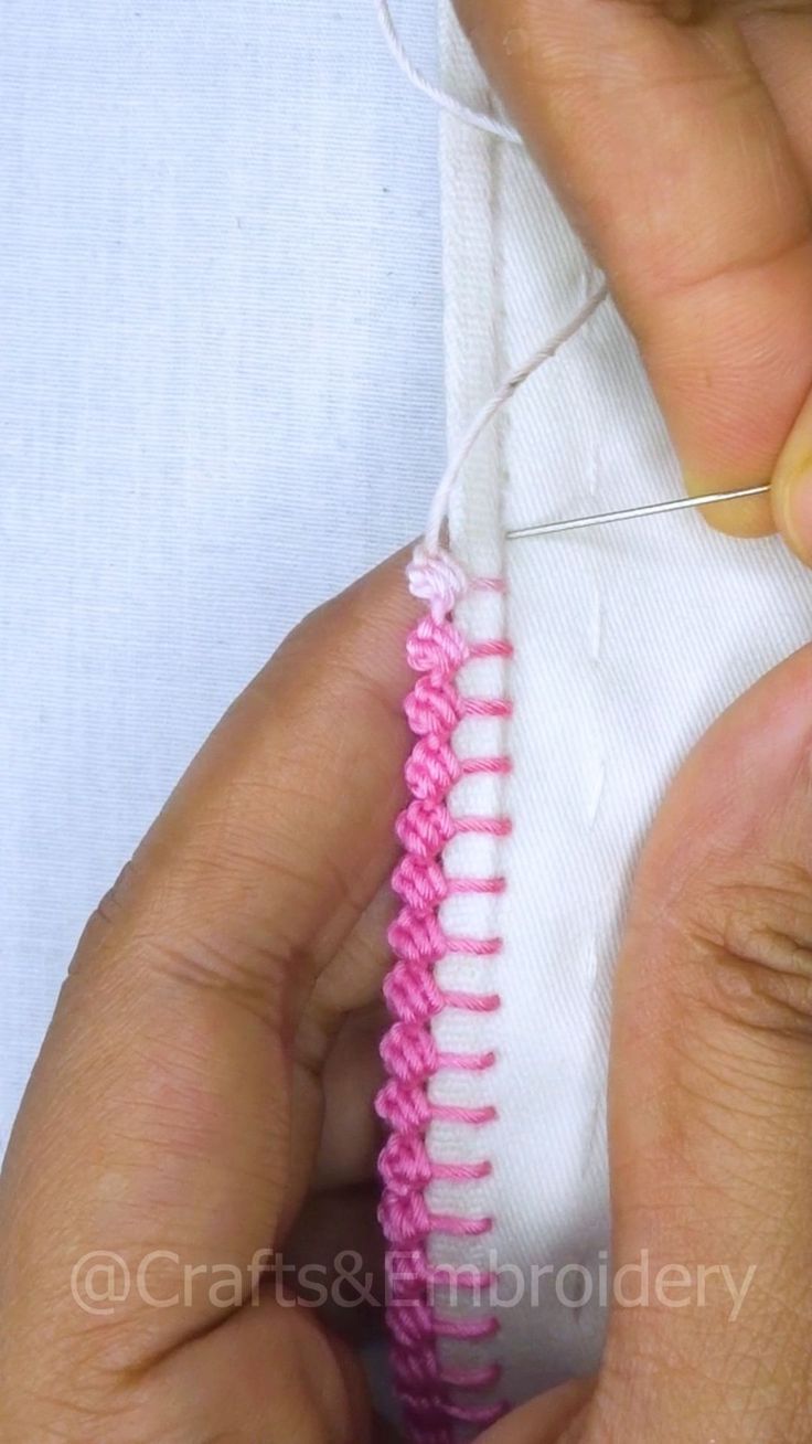 someone is stitching the end of a pink and white piece of fabric with scissors