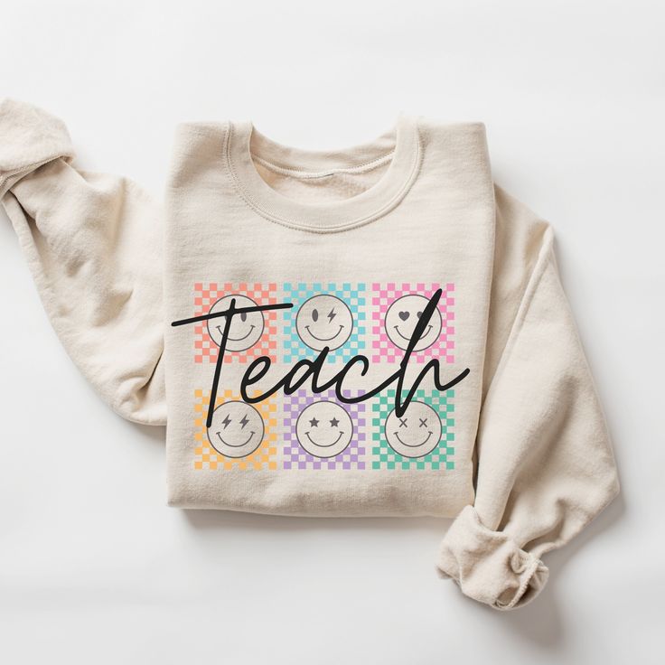 a white sweatshirt with the words teach on it and smiley faces drawn in black ink