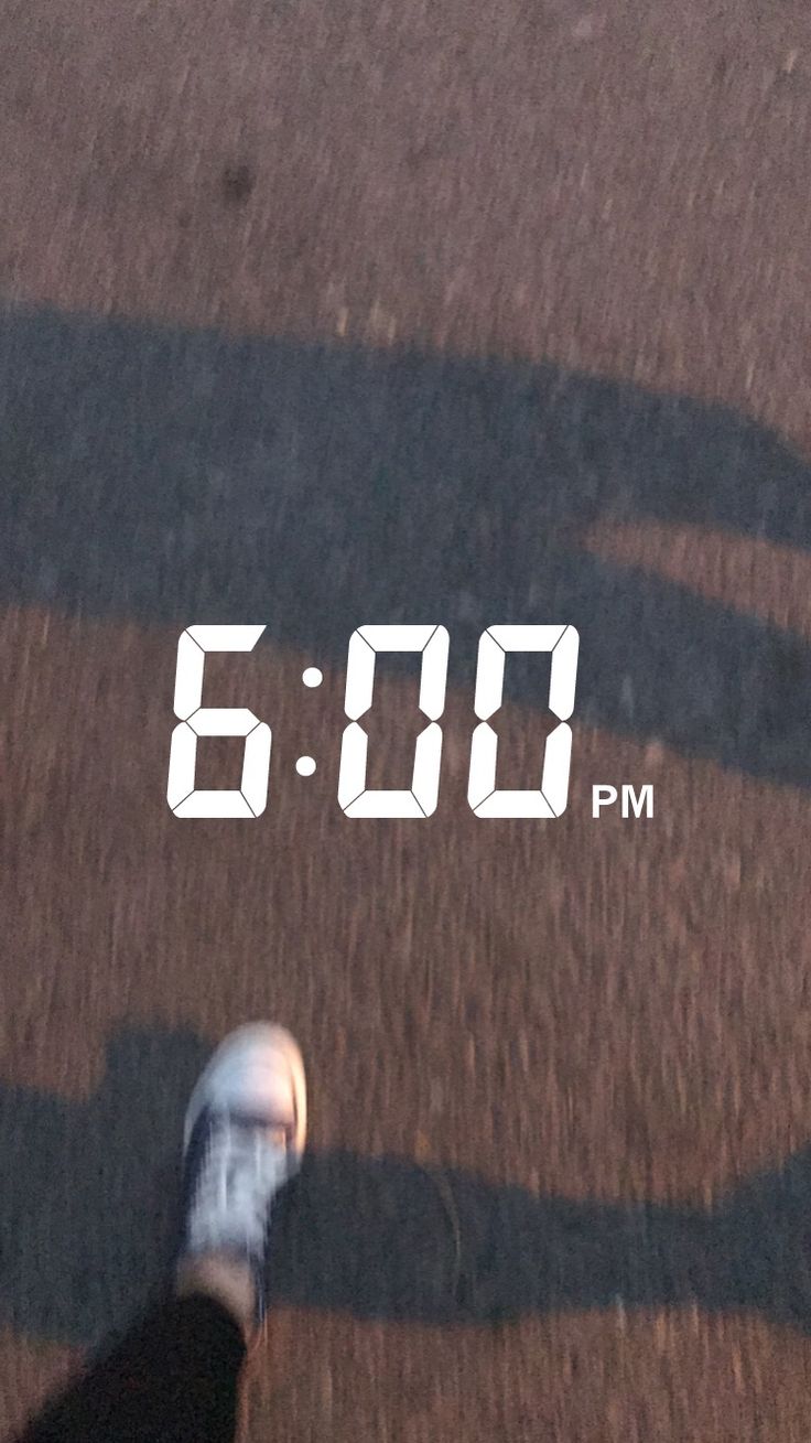 a person is walking down the street with their shadow on the ground and an alarm clock in the background