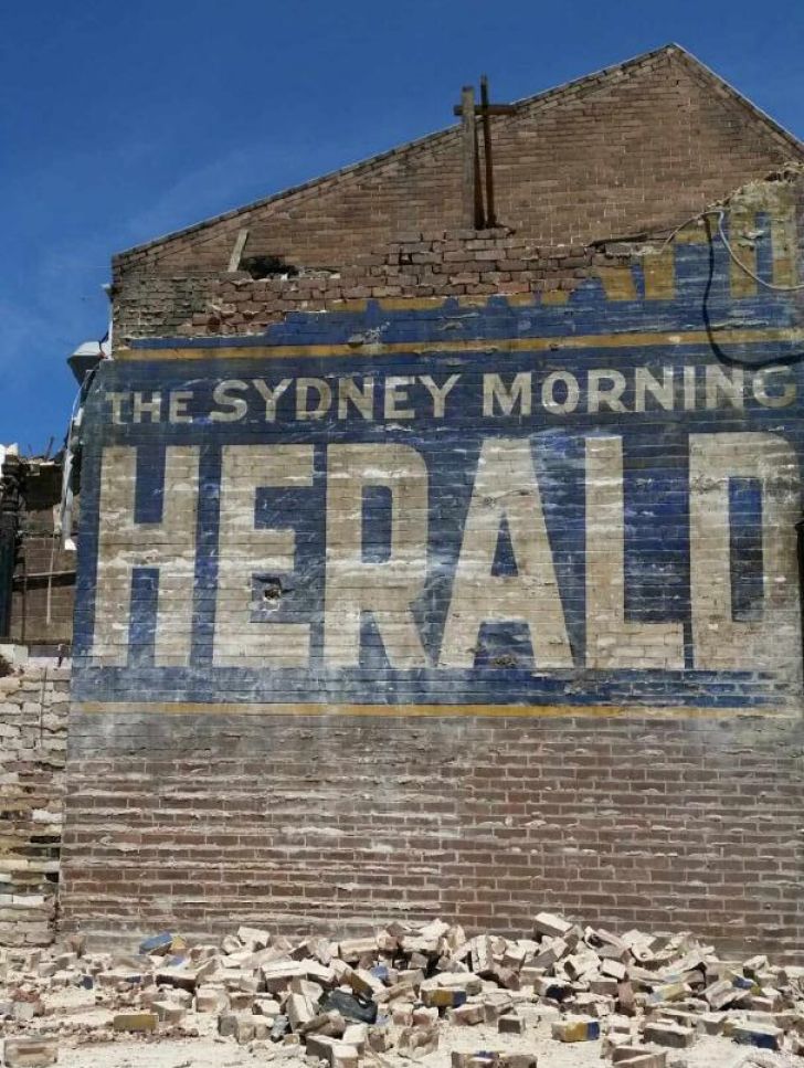 an old sign on the side of a building that says, the sydney morning herald