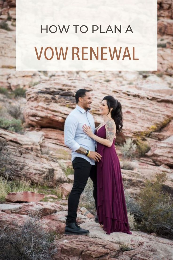 a man and woman standing on top of a rocky hill together in front of red rocks