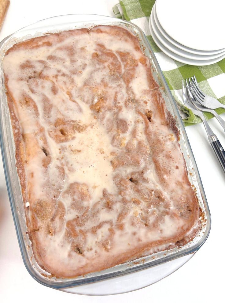 a casserole dish on a table with silverware and green checkered napkin