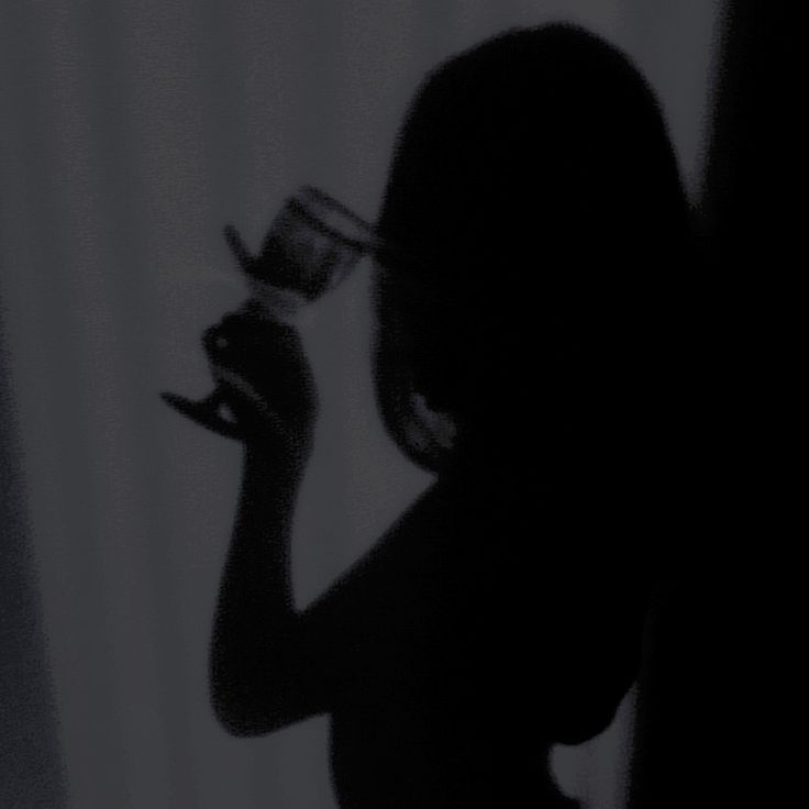 the silhouette of a woman holding a wine glass in her right hand and looking down