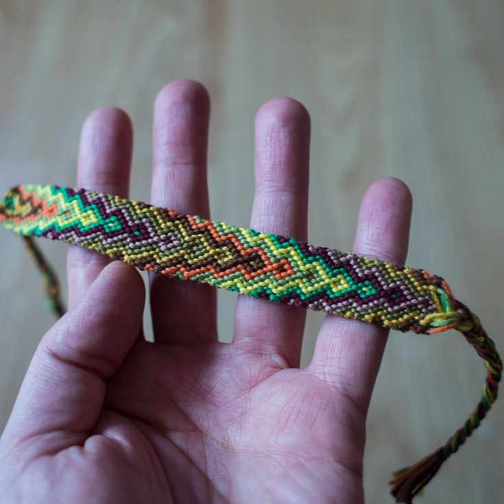 a hand holding a small colorful beaded object