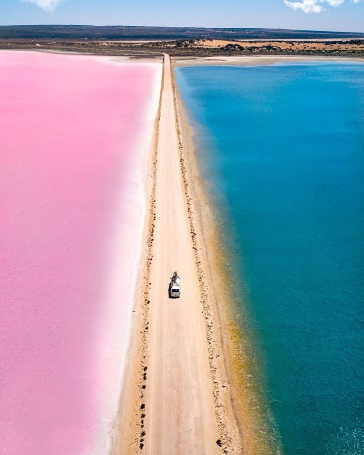 an aerial view of a boat in the water with pink sand and clear blue skies