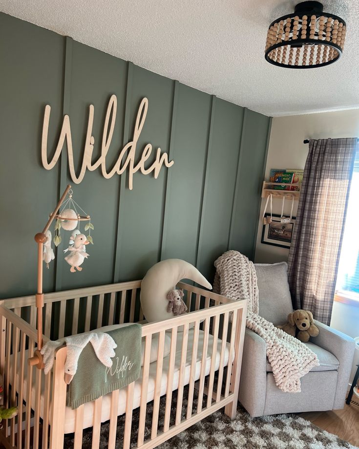 a baby's room with a crib, rocking chair and teddy bear on the wall