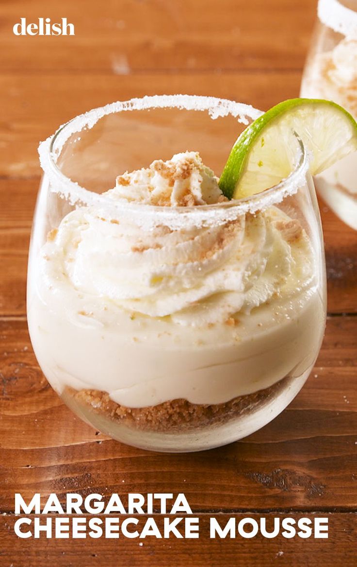 two glasses filled with dessert sitting on top of a wooden table