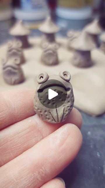 a person is holding a tiny clay frog