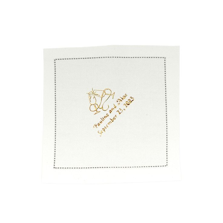 a white napkin with gold foil on the front and bottom, featuring an embroidered monogrammed