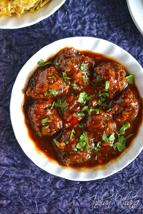 a white plate topped with meatballs covered in sauce and garnished with cilantro