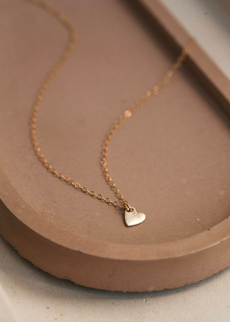 Take dainty and adorable to the next level with our Tiny Heart necklace. Made with our most delicate, everyday chain, this subtle heart charm necklace is a sweet salute to Valentine's Day. 15" of our delicate chain + 1" of extender chain. Available in 14kt Gold Fill + Sterling Silver. Shown on Abbie layered with our Maeve Chain. Handmade in Eau Claire, WI. All of our jewelry is handmade to order just for you so each piece will be unique and may vary slightly from what is pictured. Cheap Heart Pendant Necklace With Short Chain, Cheap Chain Necklace With Heart Charm For Gifting, Cheap Trendy Heart Necklace With Adjustable Chain, Cheap White Dainty Charm Necklaces, Cheap Dainty Heart Pendant Necklace, Cheap Dainty Heart Necklace For Women, Luxury Dainty Heart Necklace With Delicate Chain, Cheap Delicate Chain Pendant Jewelry, Affordable Silver Dainty Charm Necklace