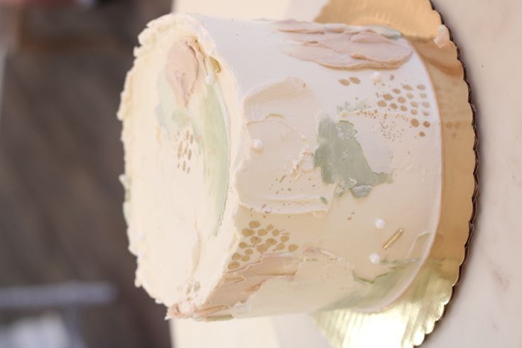 a white cake sitting on top of a table covered in frosting and gold foil