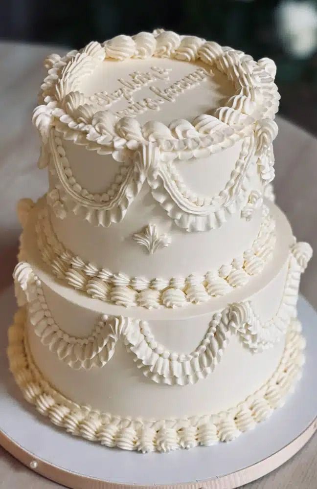 a three tiered white wedding cake sitting on top of a table