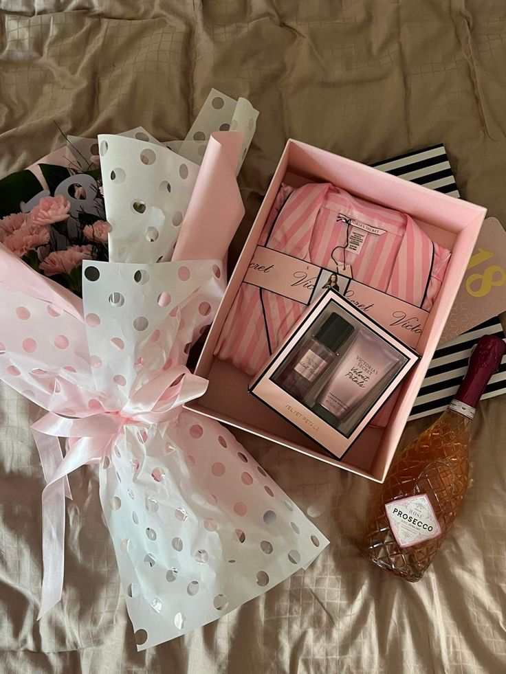 an open gift box on top of a bed next to a bottle of booze