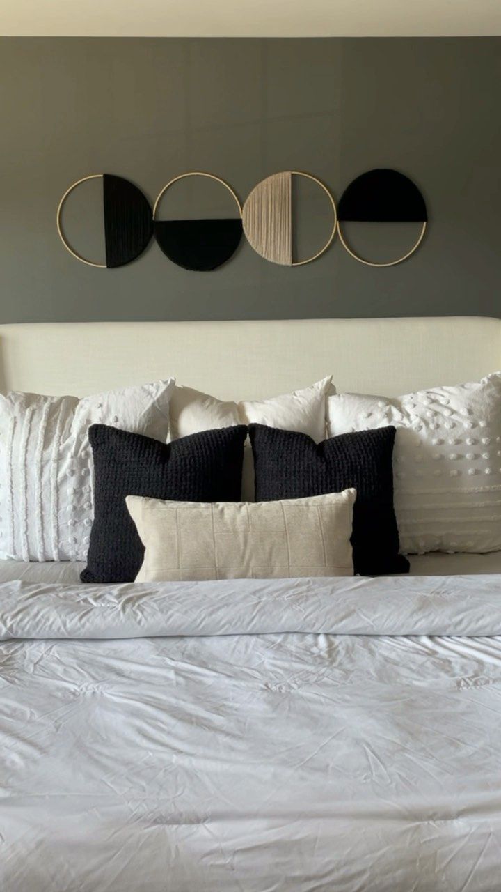 a white bed topped with pillows and two black circles above the headboard, in a bedroom