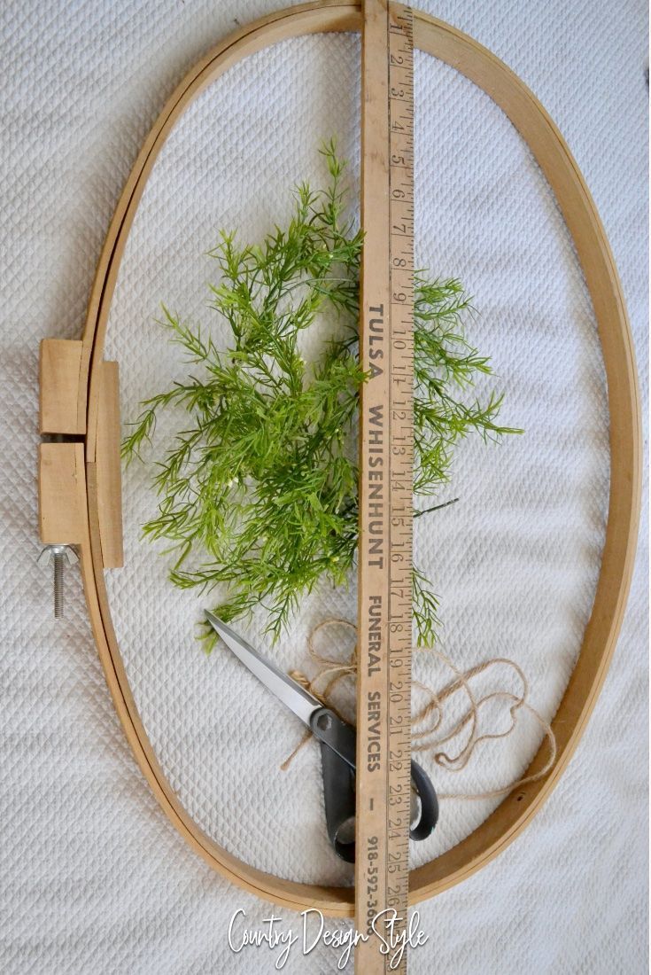 a plant is growing out of the center of a wooden hoop with measuring tape around it