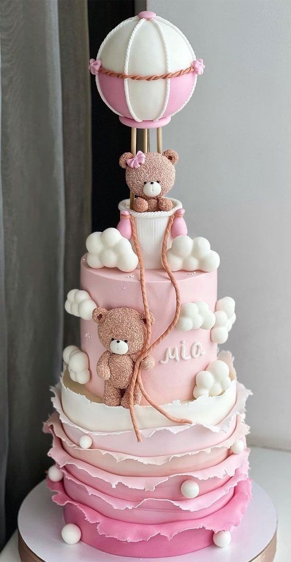 a pink and white cake with teddy bears on top