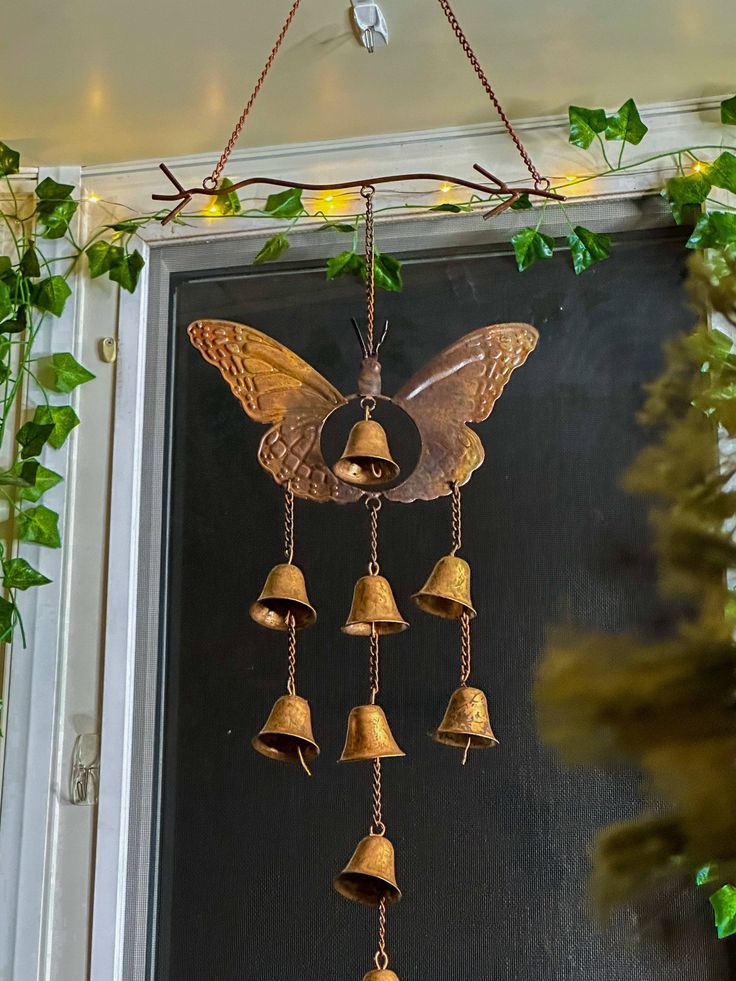 a metal bell hanging from the side of a door with bells attached to it's sides