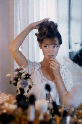 a woman sitting at a table in front of a mirror with her hands on her head