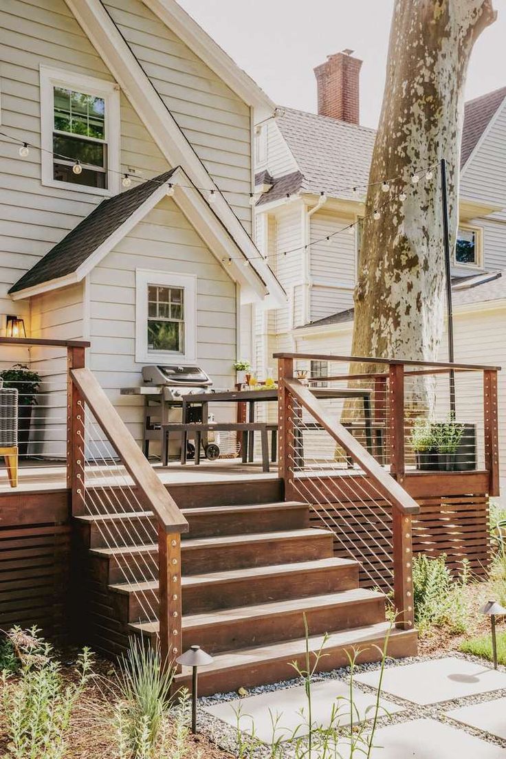 a house with stairs leading up to the front door and patio in the back yard