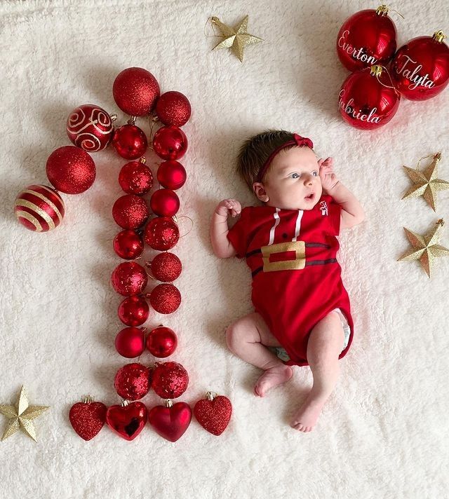 a baby is laying next to christmas ornaments