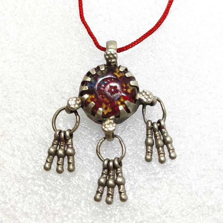 Handmade Vintage Rare Real Old High Grade Silver Small Dangles Ethnic Tribal Charm Banjara Traditional Red Stone Bell Pendant Necklace With Colour String.... Made By someone else. Discovered and collect by me from a small tribal banjara village of Rajasthan. Primary Color of Necklace is Vintage Silver, Pre- Owned, Old looks. Necklace Weight 6.9 gms. Length of Pendant With Dangles 4. cm Width of Pendant 2.8cm. It's a totally Handmade vintage tribal Silver Pendant from Rajasthan state Northern India. Your Feedback is very Important for us so leave positive Feedback. If you have any Problem or you are not satisfied with our product so Please Contact us before leaving negative Feedback. We also Believe is Customer Satisfaction. Red Necklaces With Motifs For Gifts, Bohemian Necklaces With Motifs For Gift, Bohemian Necklaces With Motifs As Gift, Red Tassel Necklaces As Gifts, Red Tassel Necklaces For Gifts, Red Tassel Necklace For Gift, Traditional Red Round Pendant Jewelry, Red Motif Jewelry For Rituals, Bohemian Jewelry With Motifs For Celebration