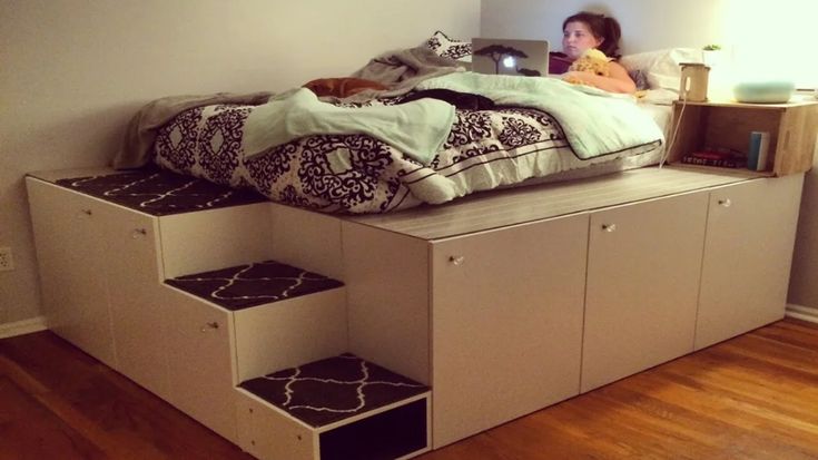 a woman sitting on top of a bed in a room with stairs leading up to it